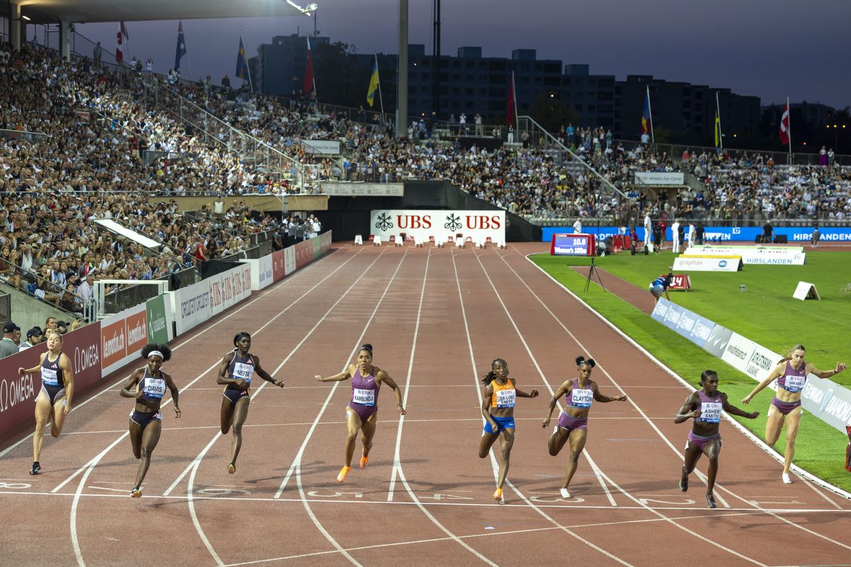 Des athlètes franchissent la ligne d'arrivée lors d'une course d'athlétisme dans un stade bondé.