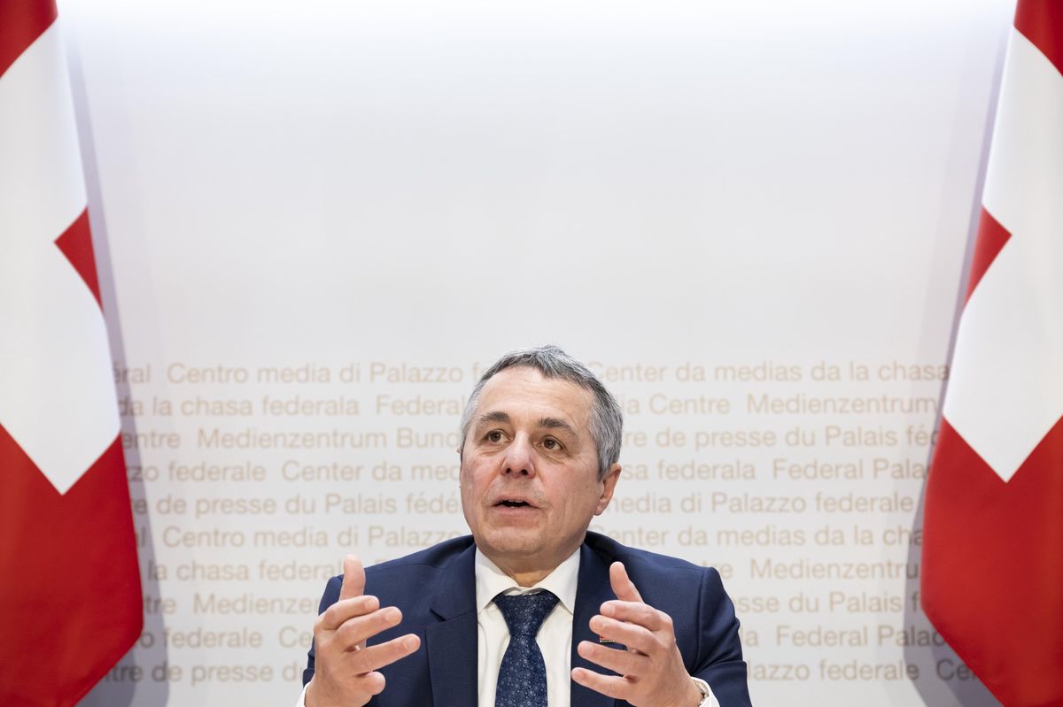 Ignazio Cassis lors d’une conférence de presse sur l’initiative pour la neutralité suisse au Palais fédéral à Berne, entre deux drapeaux suisses.