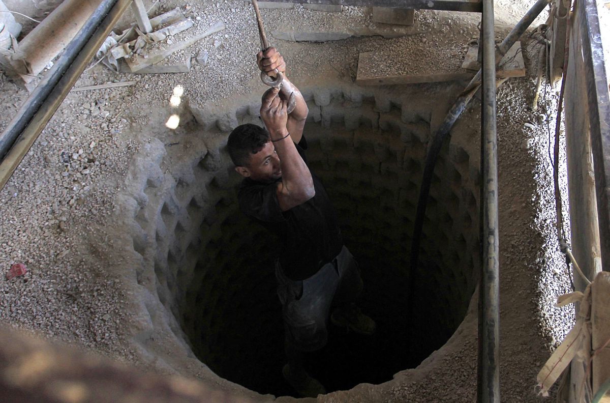(FILES) A Palestinian worker is lowered on a rope into a smuggling tunnel dug beneath the Gaza-Egypt border in the southern Gaza Strip on August 27, 2013. A sprawling network of Hamas tunnels under the Gaza Strip has become a primary target for the Israeli military in its stated mission to defeat the Palestinian militants, experts say. (Photo by Said KHATIB / AFP)