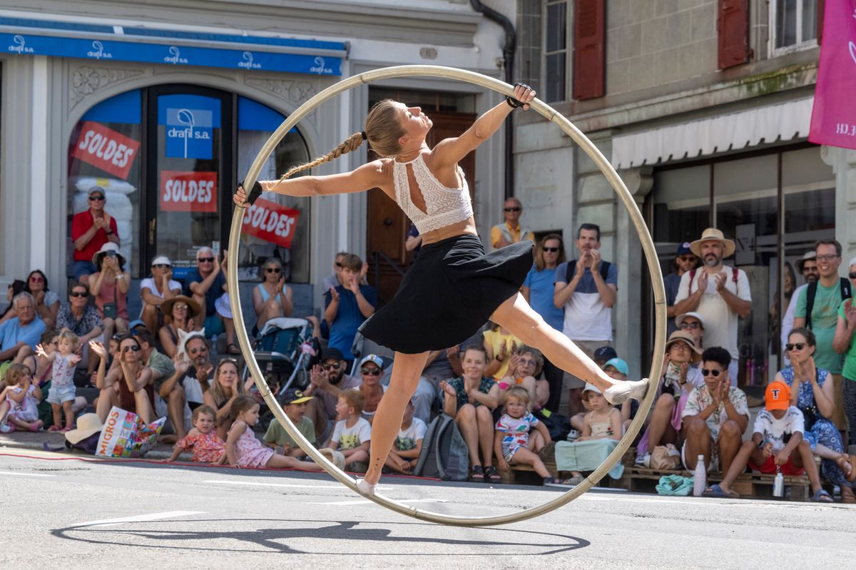 Pauline Zoé se produit avec un cerceau lors du Festival des Artistes de Rue à Vevey, avec une foule de spectateurs en arrière-plan.