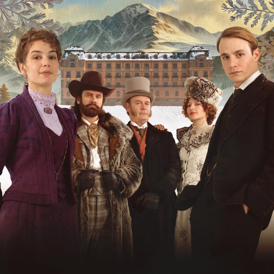 Groupe de personnes en costumes d’époque devant un bâtiment de montagne enneigé.