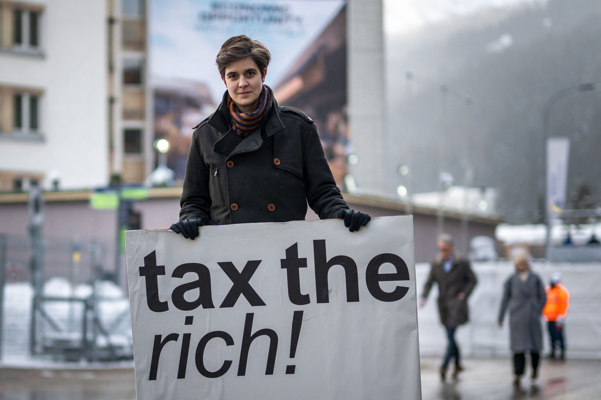 (FILES) Austrian Marlene Engelhorn, who inherited from her family who owns the Germany's chemical giant BASF, poses with a placard reading "Tax the rich!" at the entrance of the Congress center on the opening of the annual meeting of the World Economic Forum (WEF) in Davos, on January 15, 2024. The citizens group "Guter Rat" (good advice) tasked by Austrian-German heiress Marlene Engelhorn to give away the bulk of her multi-million euro inheritance on June 18, 2024 announced on how to share the fortune. Amid a persistent cost-of-living-crisis and wealth inequality worsening around the world, Engelhorn's unique intiative has made headlines. In January 2024, the 32-year-old activist advocating for higher taxes on the rich, entrusted a team to set up a citizens council of 50 Austrians to come up with ideas how 25 million euros ($26.8 million) of her wealth should be given away. (Photo by Fabrice COFFRINI / AFP)