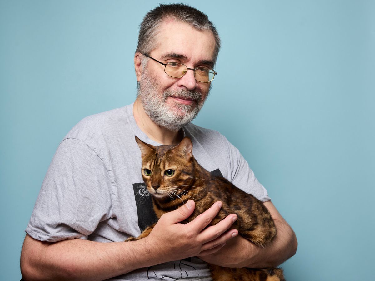 Christian tenant Mugi, un chat domestique, devant un fond bleu à Thônex, le 29 juillet 2024.