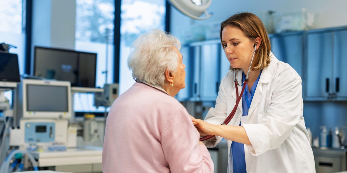 Médecin écoutant la respiration et les battements de cœur d'une femme âgée avec un stéthoscope dans une clinique.