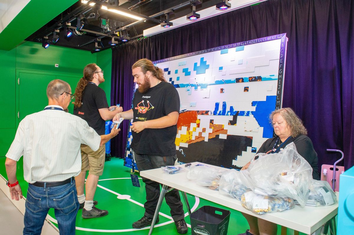 Vainqueurs de Lego Masters, Eric Bedelek et Alex Favre (en t-shirts noirs, de dos et de face) ont réalisé lundi au Musée olympique une fresque de 6 m² composée de 100 000 briques.