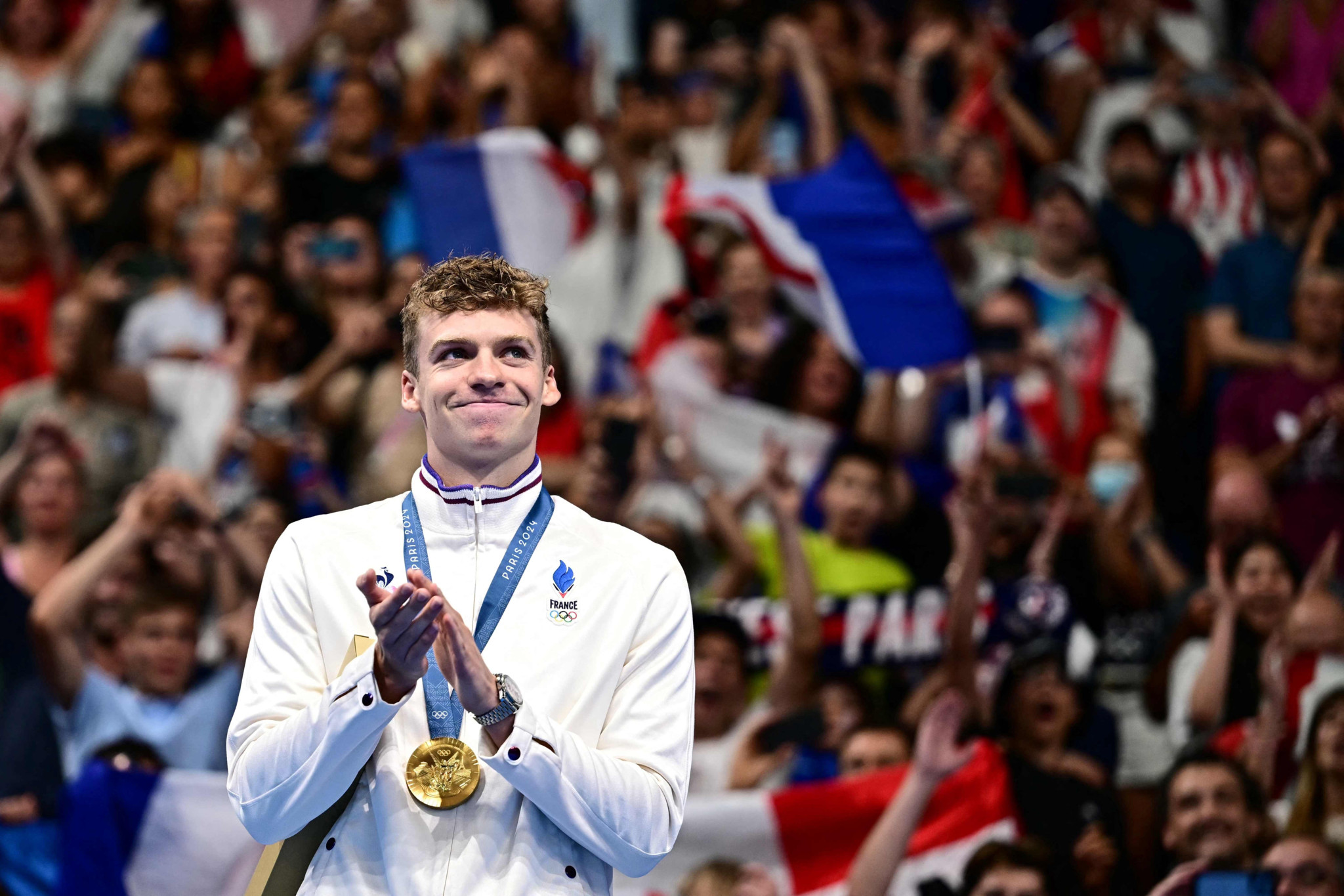 TOPSHOT - Gold medallist France's Leon Marchand poses with his medal on the podium of the men's 200m individual medley swimming event during the Paris 2024 Olympic Games at the Paris La Defense Arena in Nanterre, west of Paris, on August 2, 2024. (Photo by Manan VATSYAYANA / AFP)