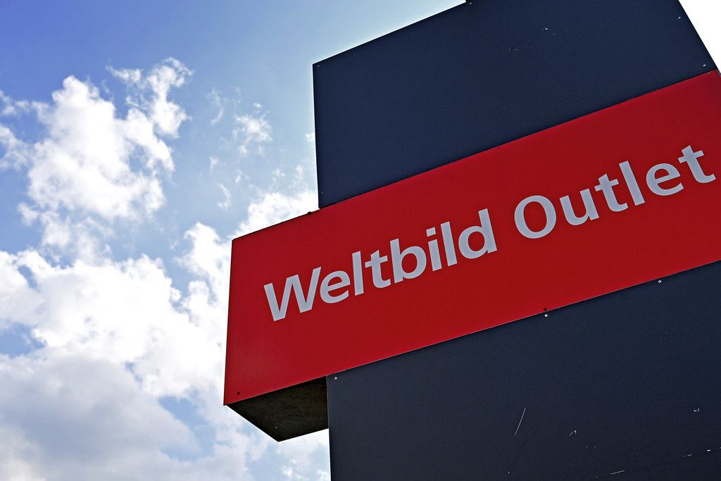 Enseigne rouge du magasin Weltbild Outlet avec un ciel nuageux en arrière-plan. Le magasin d'Augsburg ferme en raison de l'insolvabilité de l'éditeur Weltbild.