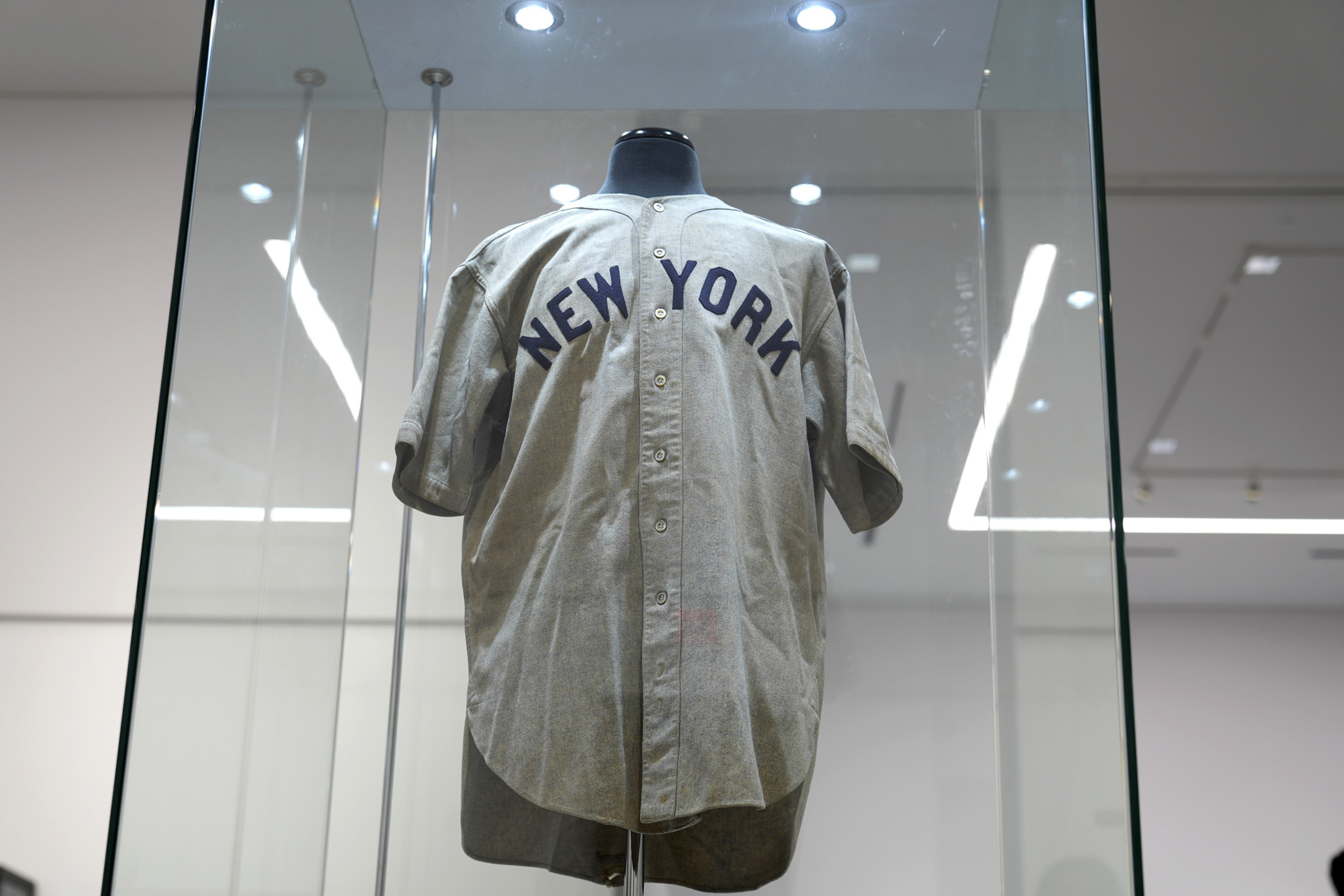 Ausgestellte Baseballuniform mit der Aufschrift 'New York' in einer Glasvitrine.