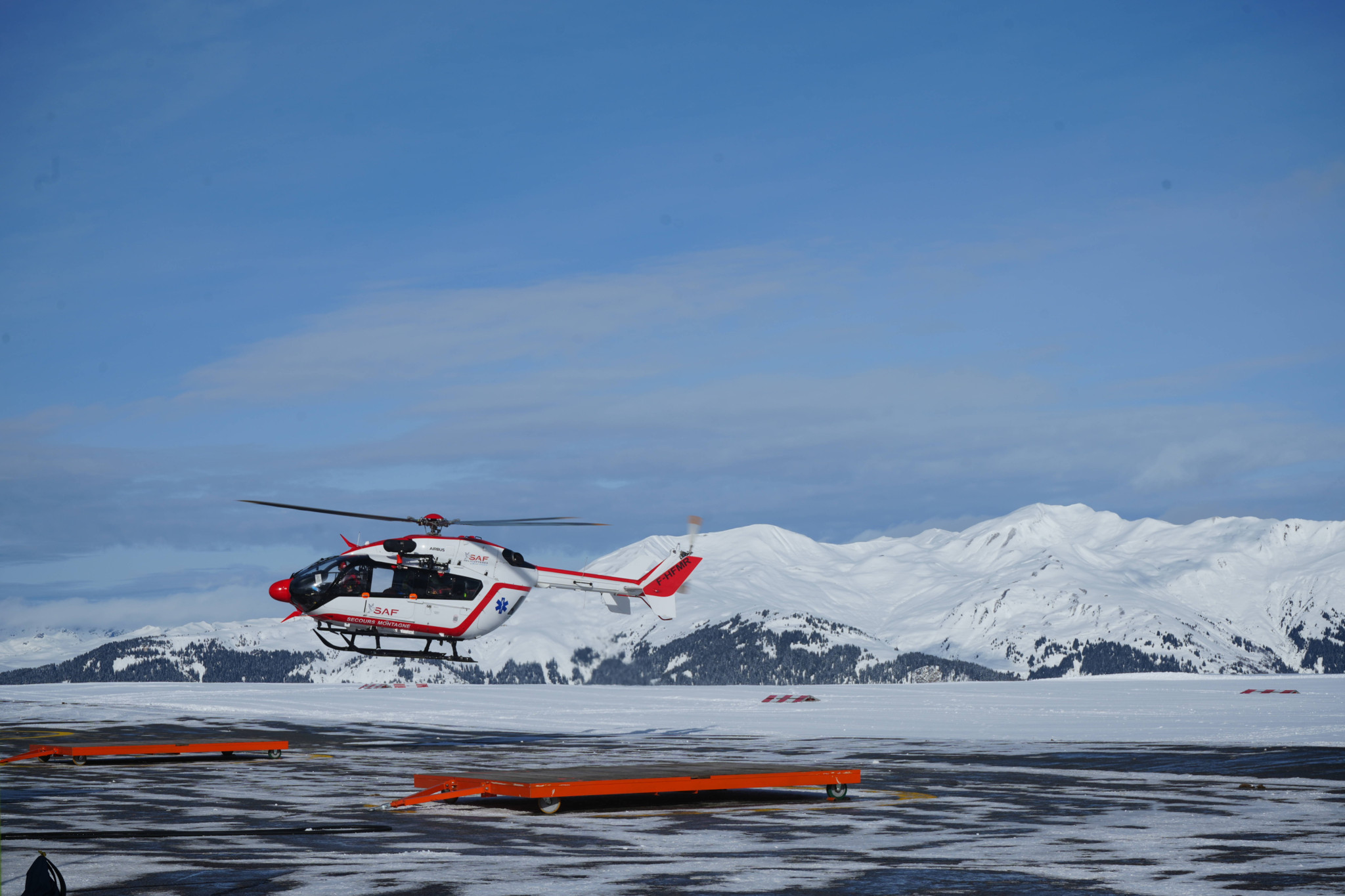 Rescue helicopter in Savoie during deadly avalanches in the French Alps, January 2026, with snow-capped peaks in the background.