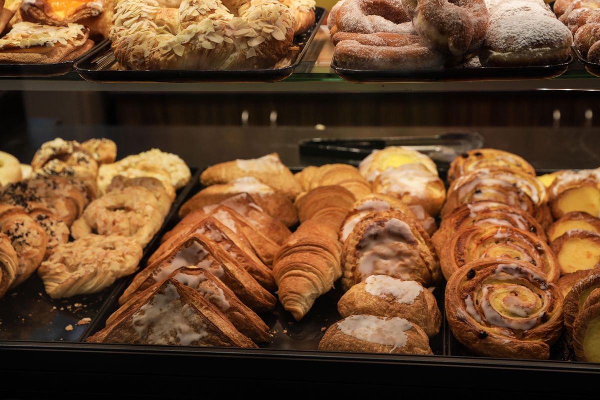 Vitrine de pâtisserie avec une variété de viennoiseries, y compris croissants, pains au chocolat et brioches.
