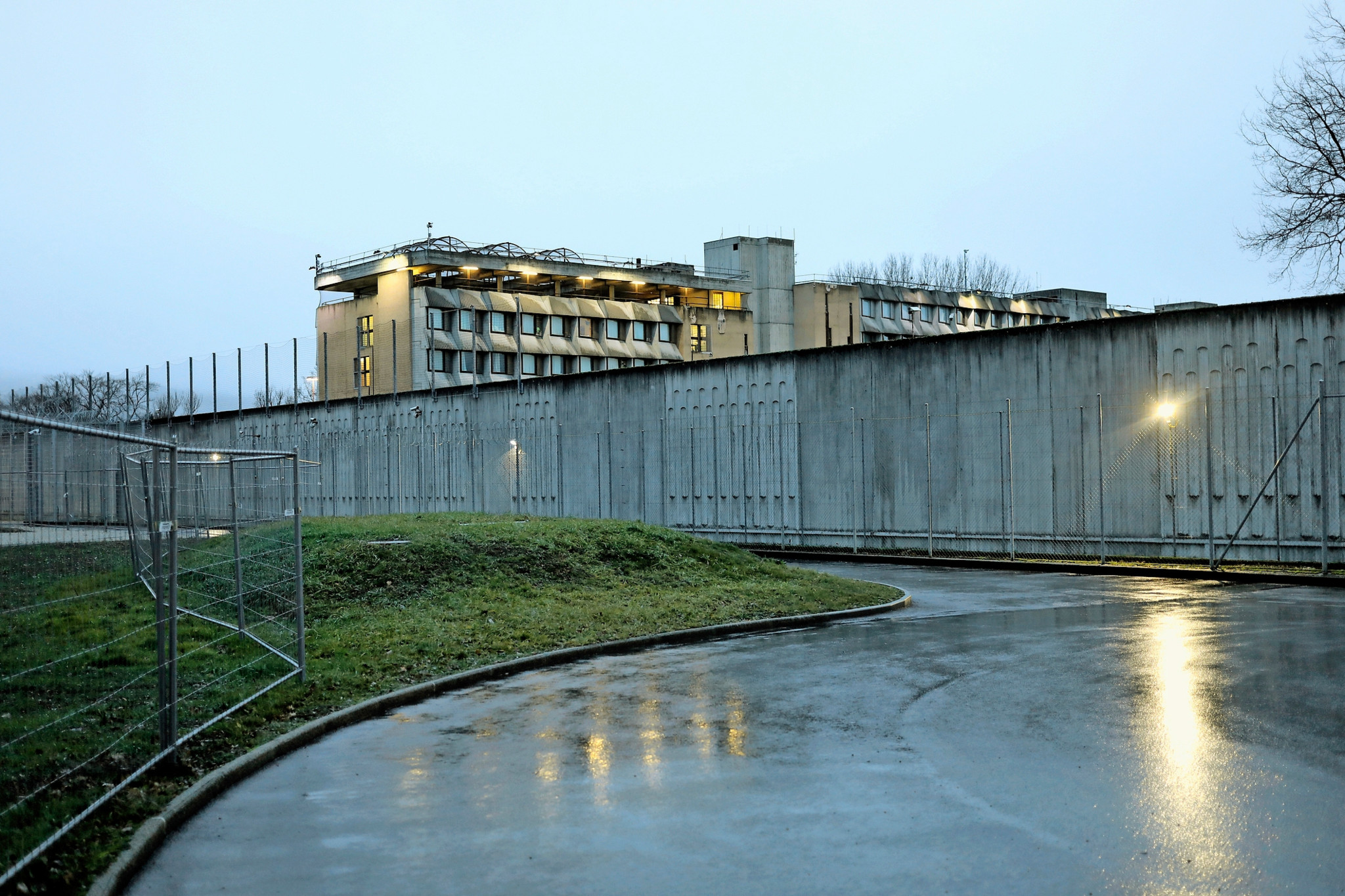 Prison de Champ-Dollon à Genève avec lumière du soir et pavé mouillé. Manifestation de gardiens prévue pour le départ de l’ancien directeur M. Franziskakis.
