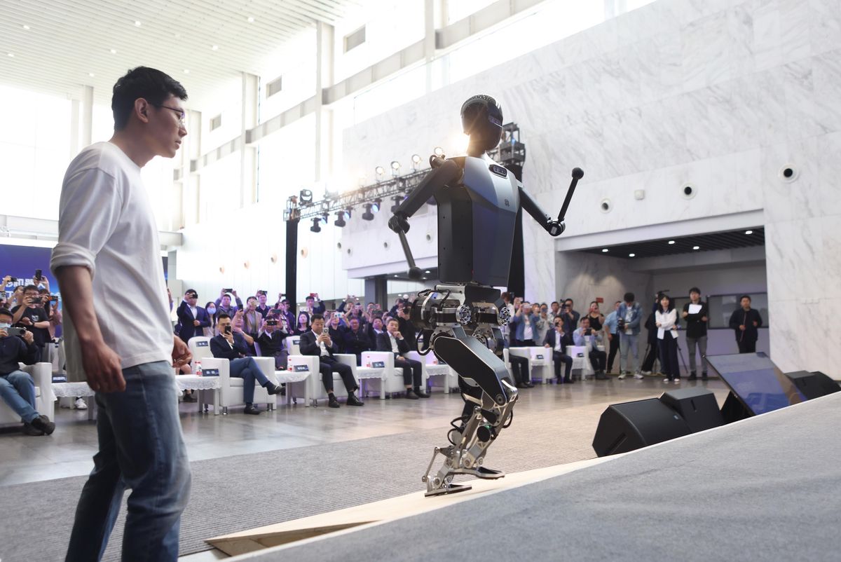 Le robot humanoïde chinois Tiangong monte une pente lors de la cérémonie de lancement à Pékin, avec des spectateurs en arrière-plan.