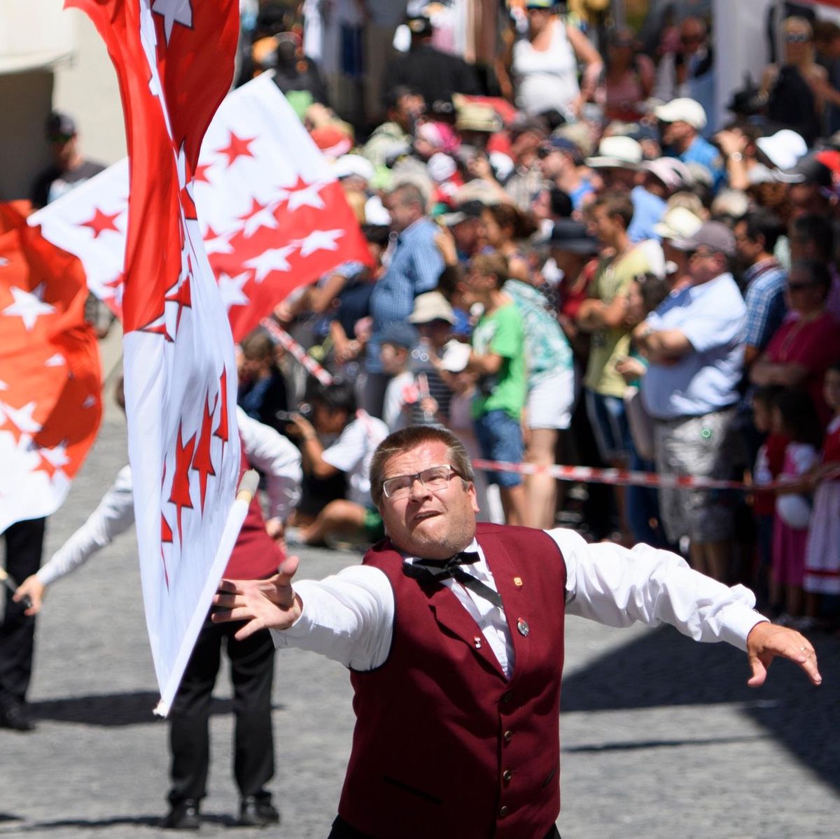 Une personne en costume traditionnel lance un drapeau valaisan lors du cortège de la 30ème édition de la Fête fédérale de jodle à Brigue, Valais.