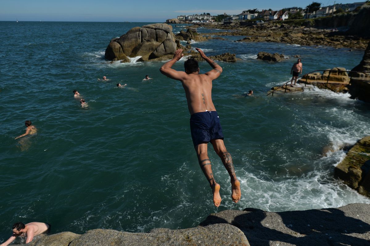 Ein Mann springt im Naturbad Forty Foot in Sandycove bei Dublin von einer Klippe.
