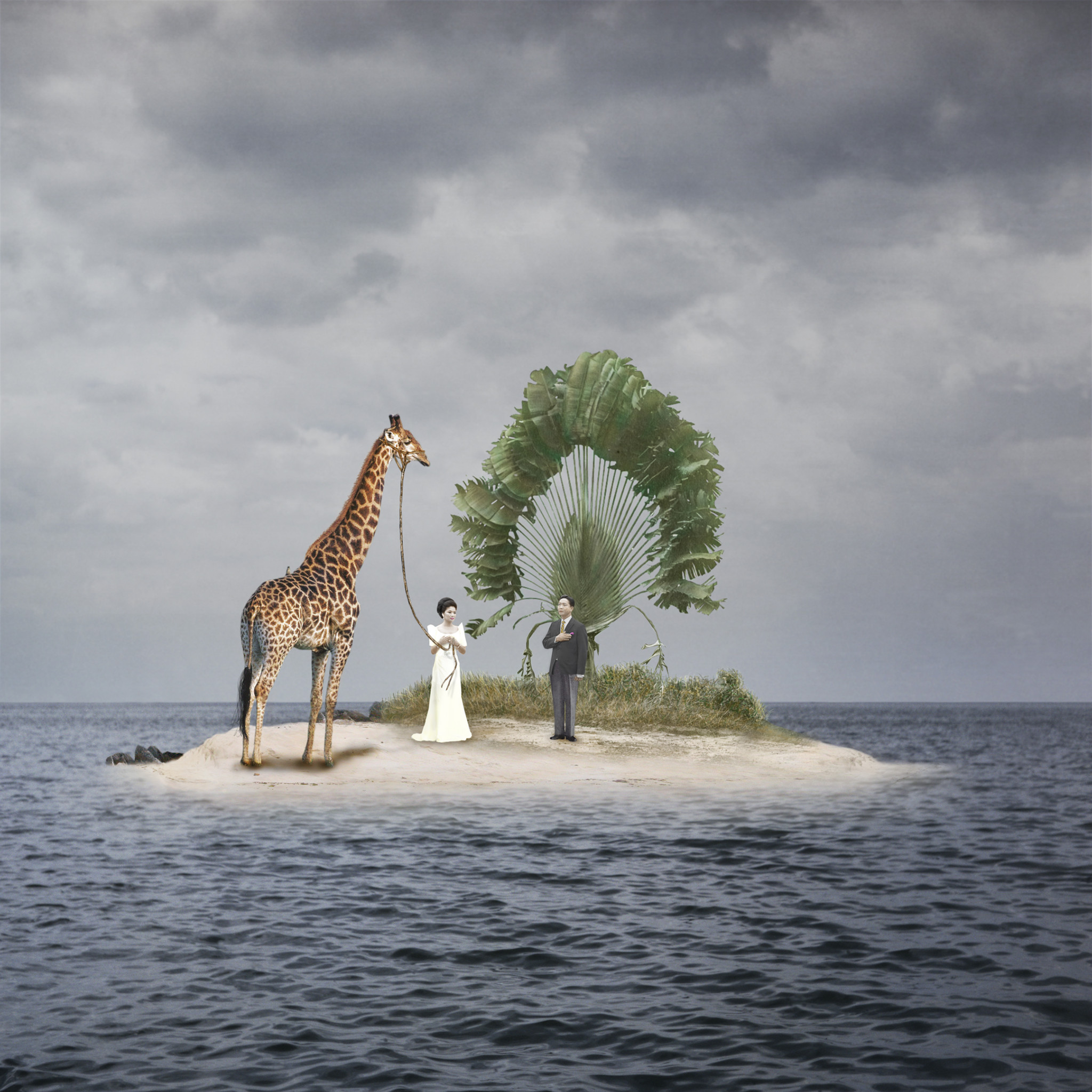 Zwei Menschen stehen mit einer Giraffe auf einer kleinen Insel im Ozean, umgeben von bewölktem Himmel.