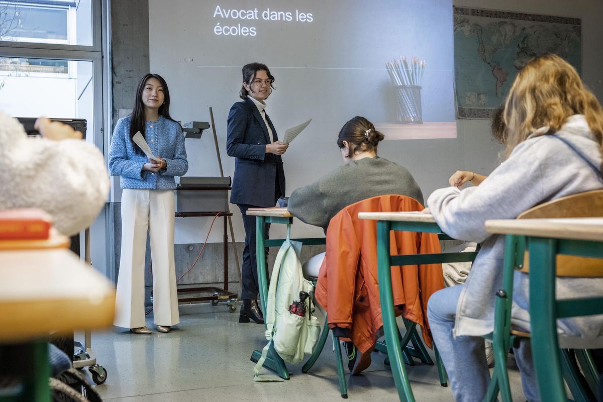 Deux avocates présentent sur le harcèlement à une classe au Cycle de l'Aubépine, Genève, avec un projecteur affichant 'Avocat dans les écoles'.