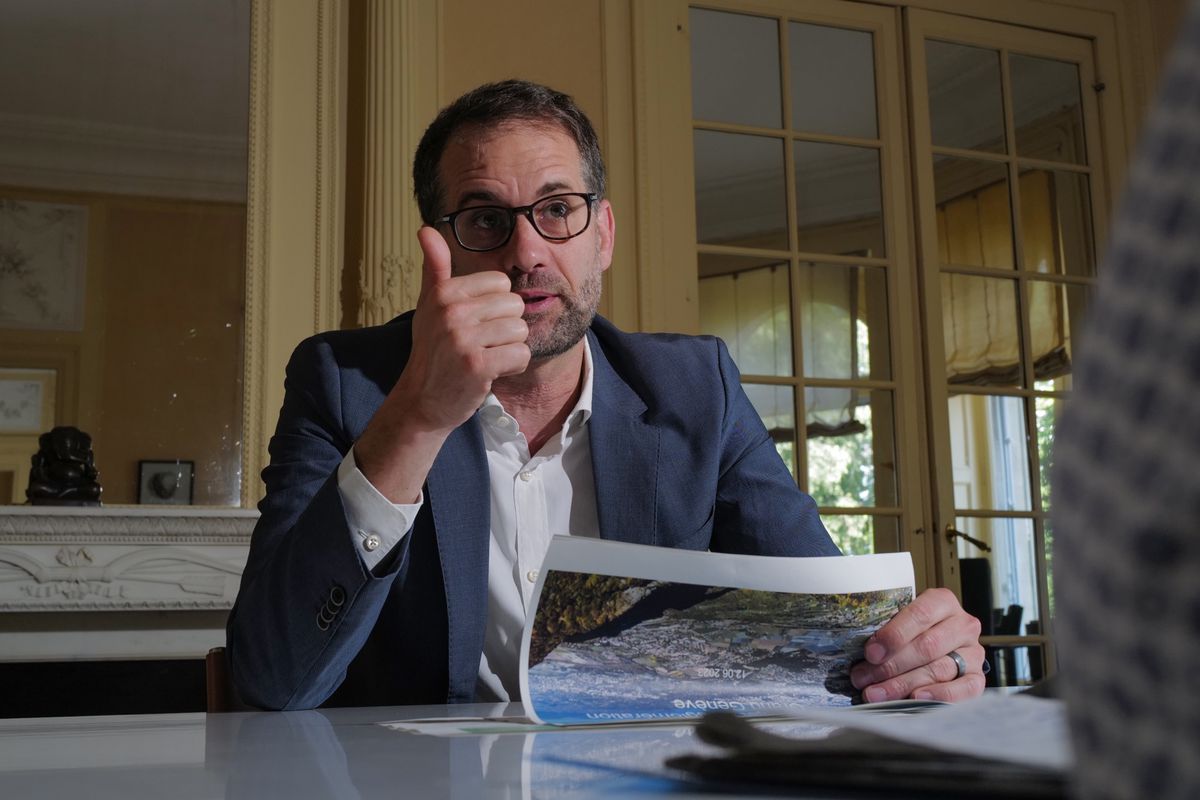 Antonio Hodgers discutant de la politique régionale genevoise au Grand Genève à l'Hôtel de Ville, tenant un document et faisant un geste de pouce levé.