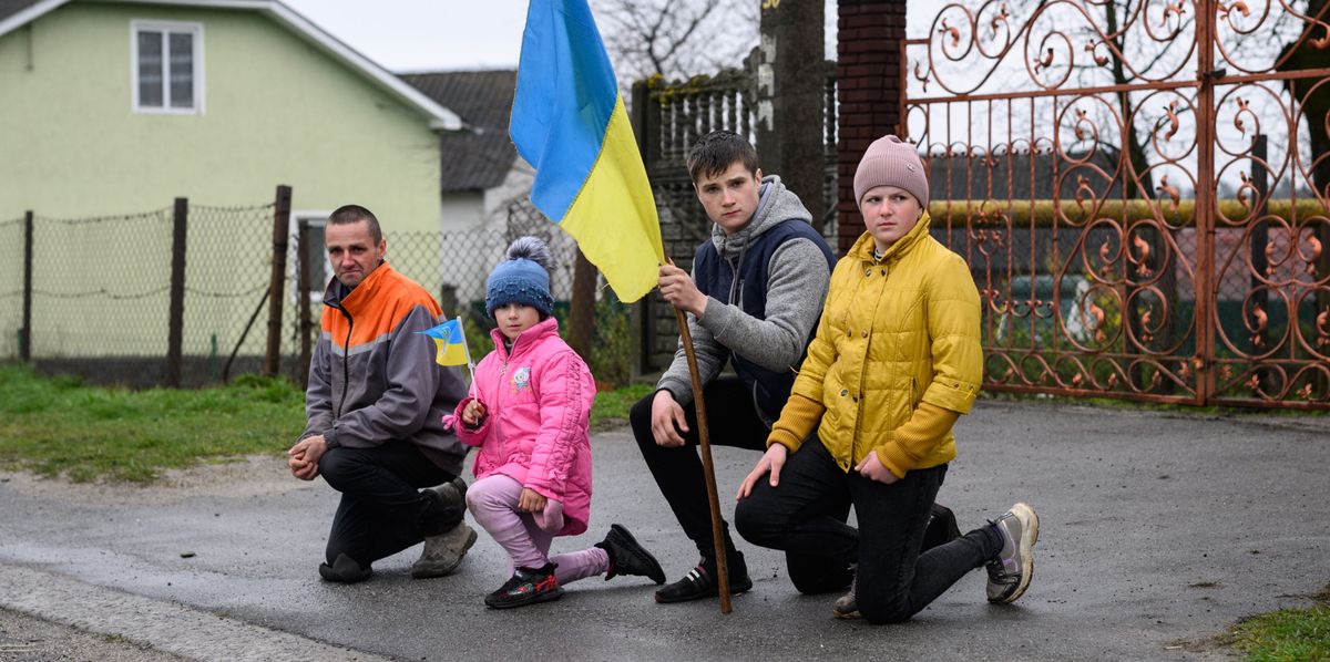 LVIV, UKRAINE - APRIL 23: Members of the local community kneel outside their homes as the funeral procession drives to the funeral service for fallen soldier Kobryn Oleg, aged 39, at the Church of Saint Jehoshaphat on April 23, 2022 in Dev'yatnyky, Ukraine. President Volodymyr Zelensky recently announced that up to 3,000 Ukrainian troops have been killed since the February 24 invasion of Ukraine. Thousands of civilians have also been killed, but estimates vary widely. (Photo by Leon Neal/Getty Images)