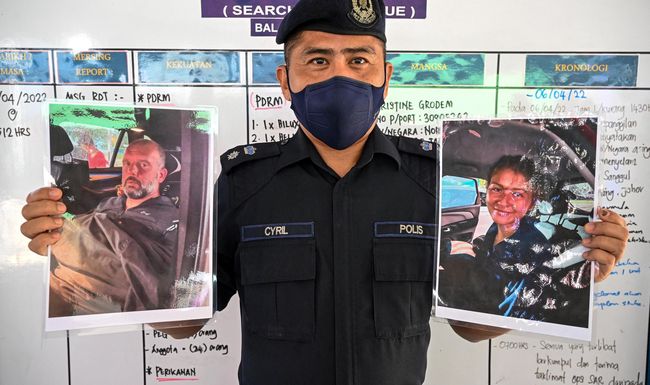 Un policier malaisien avec les photos d’Alexandra Molina (droite) et d’Adrian Peter Chesters (gauche), à Mersing, en Malaisie, samedi 9 avril 2022.