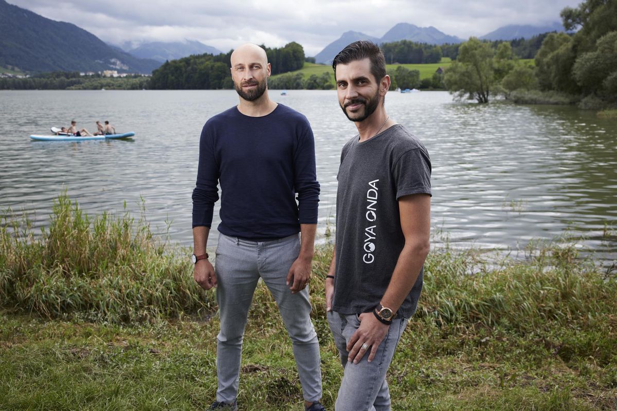 Arnaud Dorthe (g) et Flurin Mathieu (d), deux des associés de Goya Onda, posent au bord du lac de La Gruyère. Les deux entrepreneurs ont le projet de construire à cet endroit un centre aquatique avec une vague artificielle pour les surfeurs. 