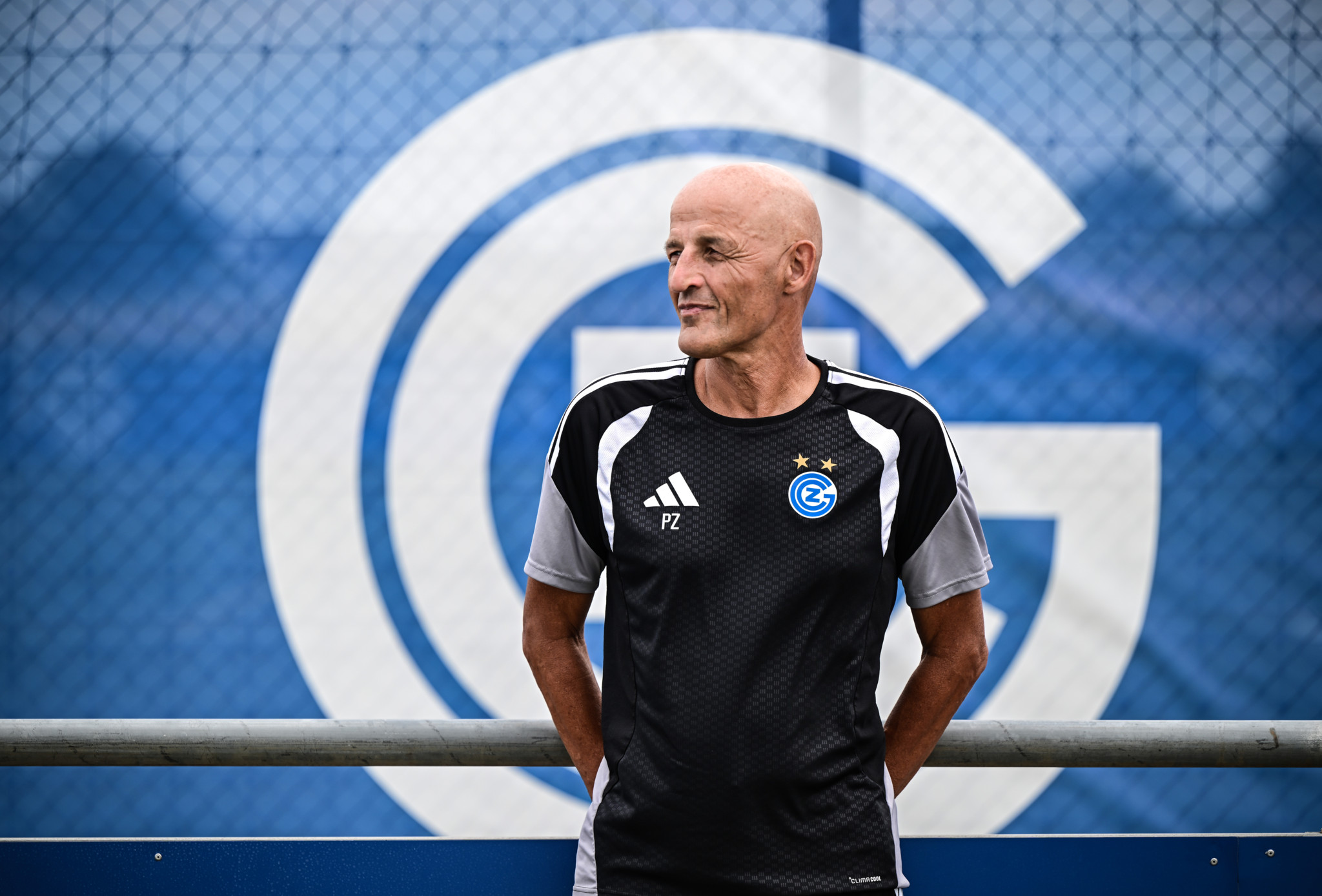 GC-Trainer Peter Zeidler im schwarzen Trainertrikot vor dem Grasshopper-Club-Logo auf dem Trainingsplatz.