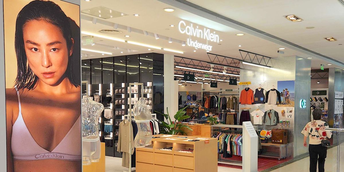 Ein Einkaufszentrum mit einem Calvin Klein Unterwäschegeschäft. Ein grosses Werbeplakat zeigt eine Frau in Calvin Klein Unterwäsche. Kleidungsstücke und Schaufensterpuppen sind im Hintergrund zu sehen.