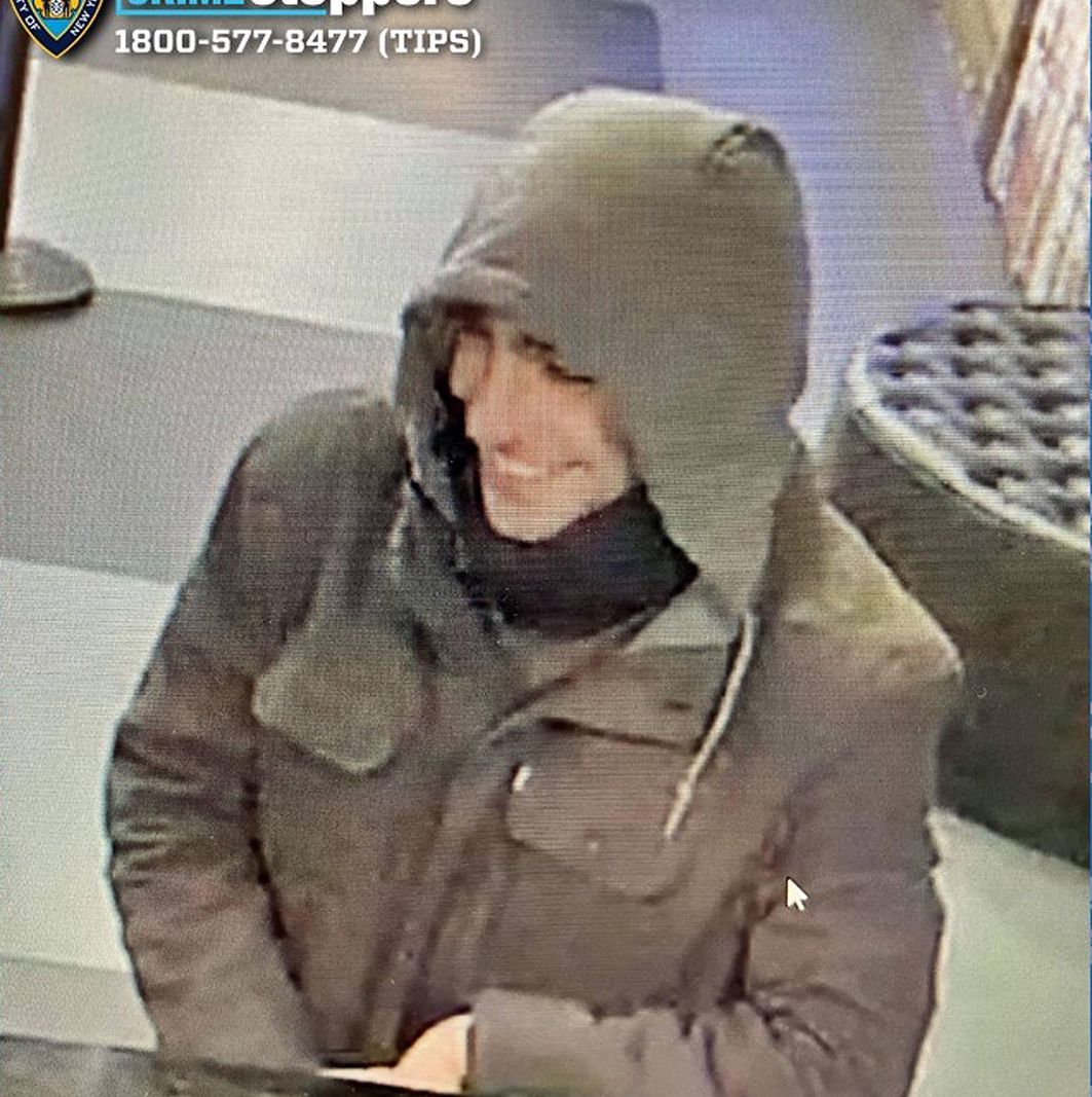 Surveillance photo d’un homme souriant portant une veste verte et un masque noir autour du cou, présumé impliqué dans une fusillade à New York.