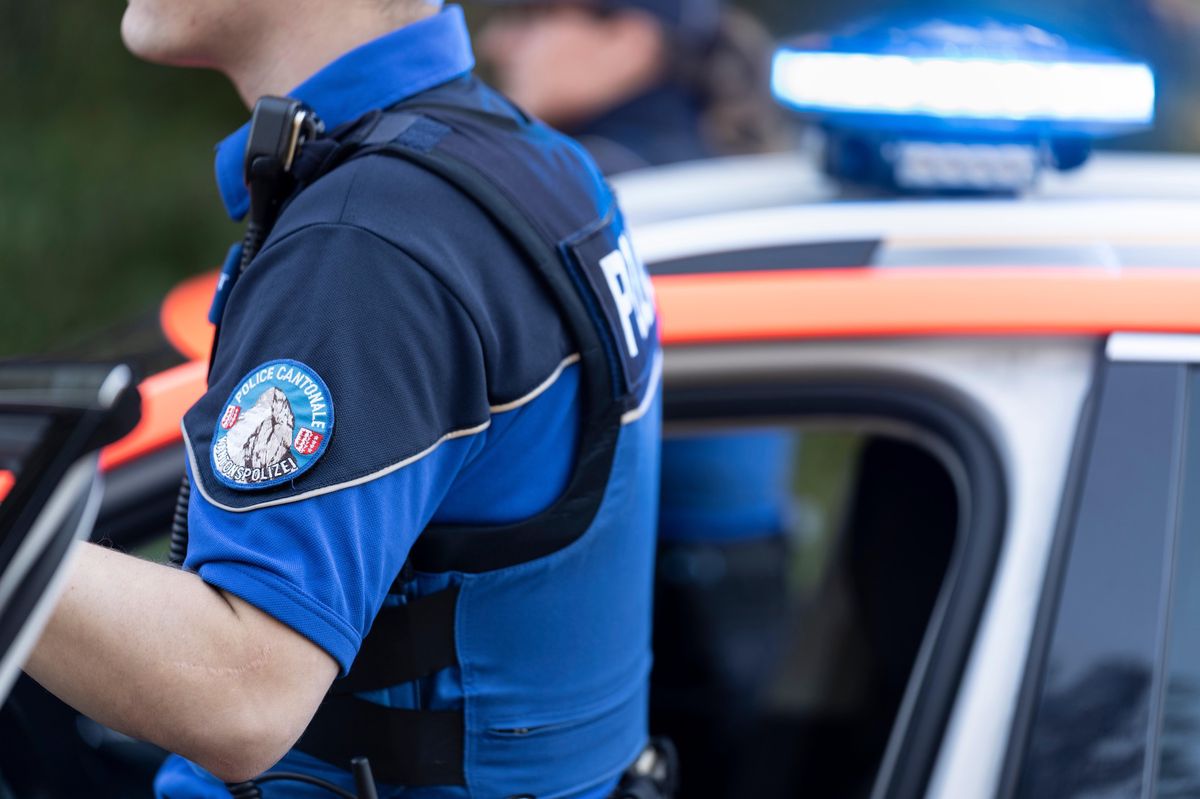 Deux policiers de la police cantonale valaisanne sortent d’une voiture de police à Raron, Valais, le 27 octobre 2021.