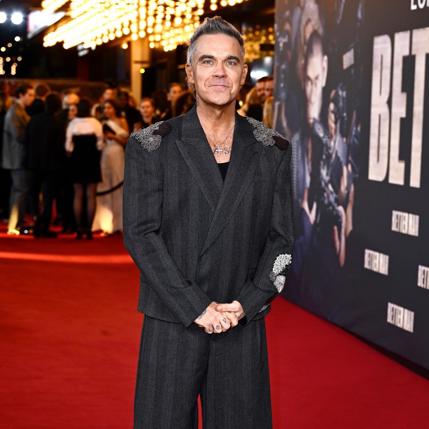 Robbie Williams pose sur le tapis rouge lors de la première du film ’Better Man’ à Londres, vêtu d’un costume sombre ample.