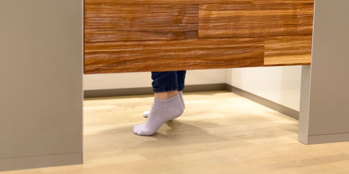 Pied en chaussettes visibles sous une porte de cabine d'essayage dans un magasin.