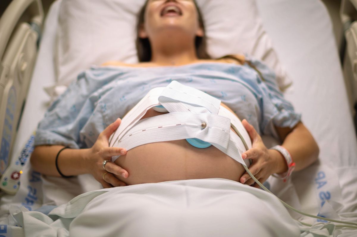 A woman having painful contractions lying in the hospital bed waiting for labor.