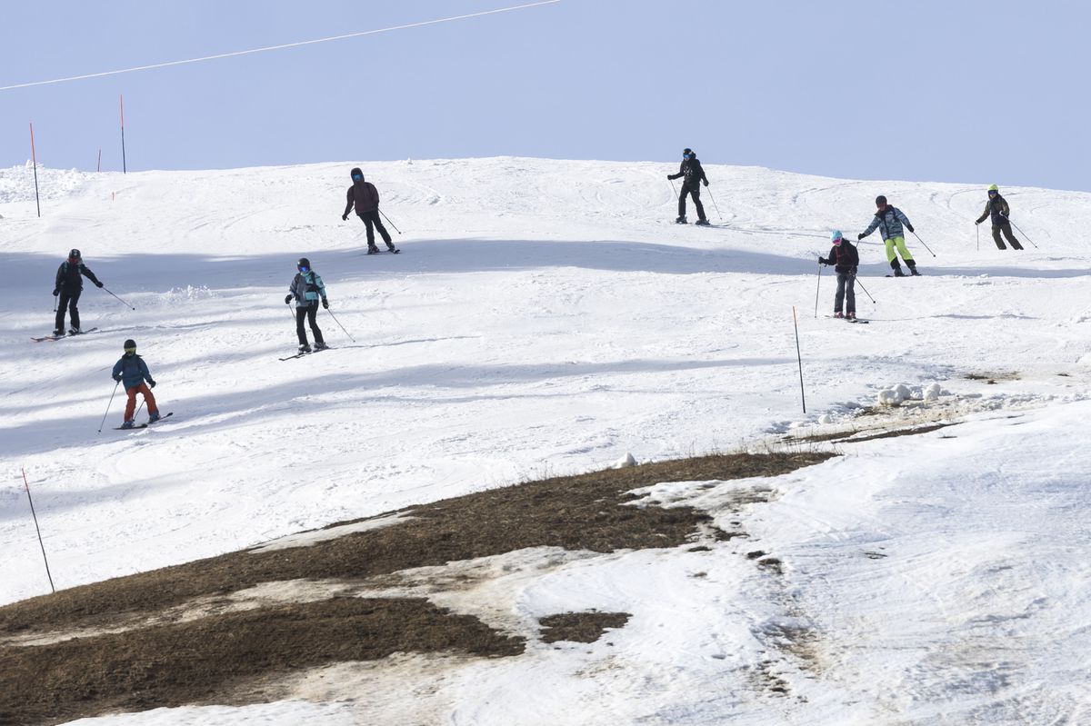 Skiers slides down a partially snow-covered ski slope, at an altitude of 1450 meters, in the Alpine resort of Les Mosses, in Ormont-Dessous, Switzerland, Tuesday, February 6, 2024. Mild weather in recent days in the Swiss Alps disrupted the activity of alpine ski resorts.(KEYSTONE/Cyril Zingaro)