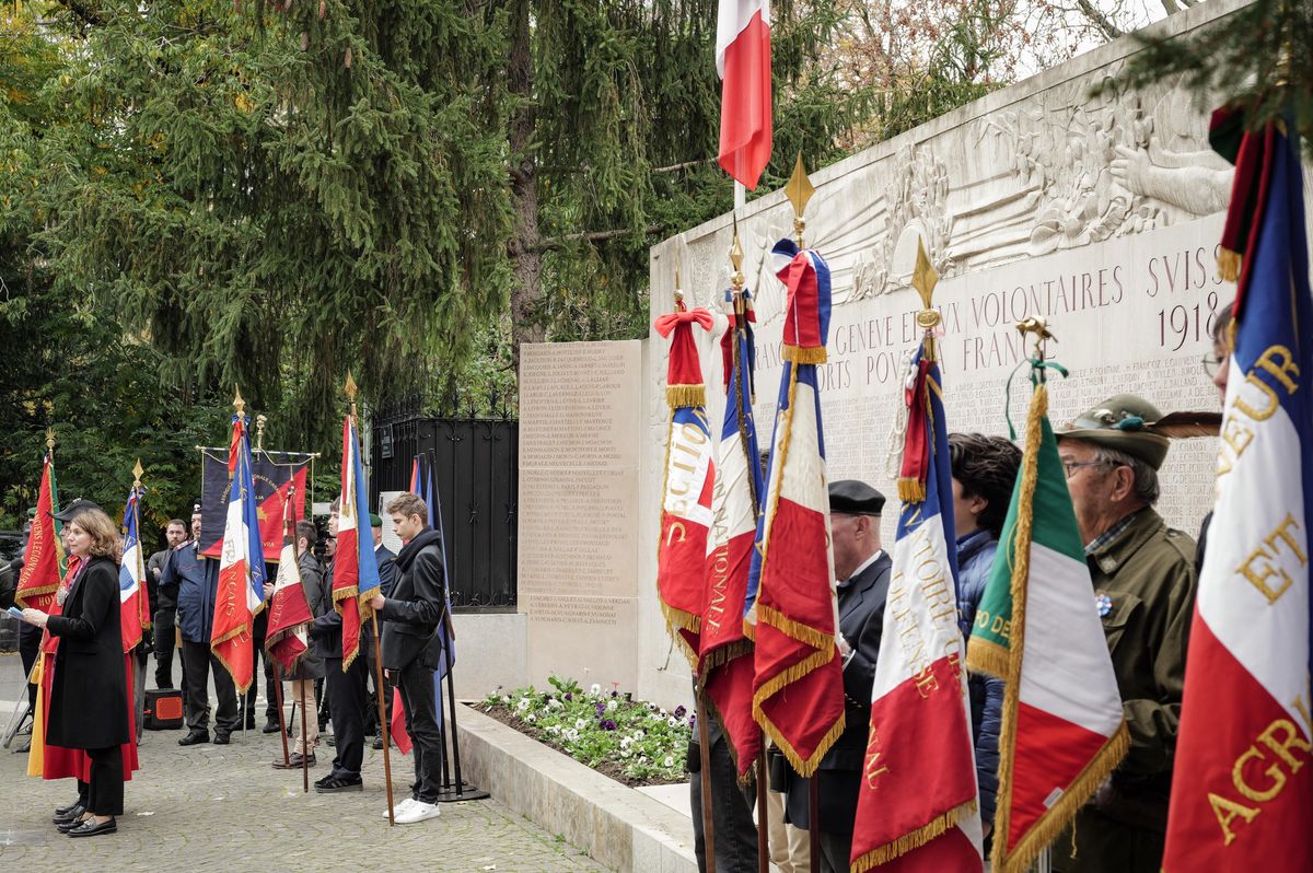 Inauguration des nouvelles stèles du Monument aux Morts franco-suisse à Genève, avec des porte-drapeaux alignés devant un mur commémoratif.