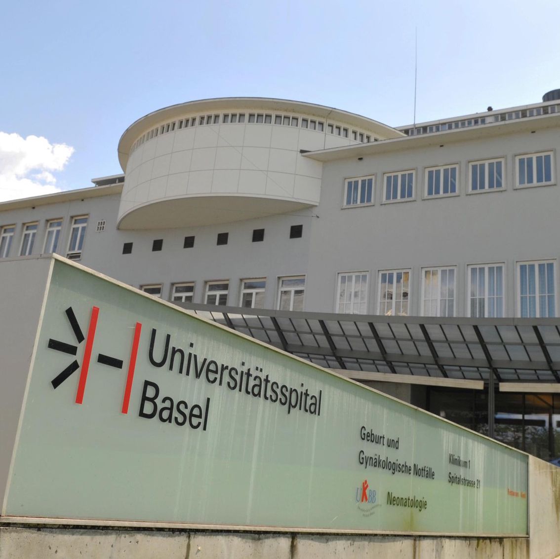 Gebäude des Universitätsspitals Basel mit sichtbarem Schild im Vordergrund.