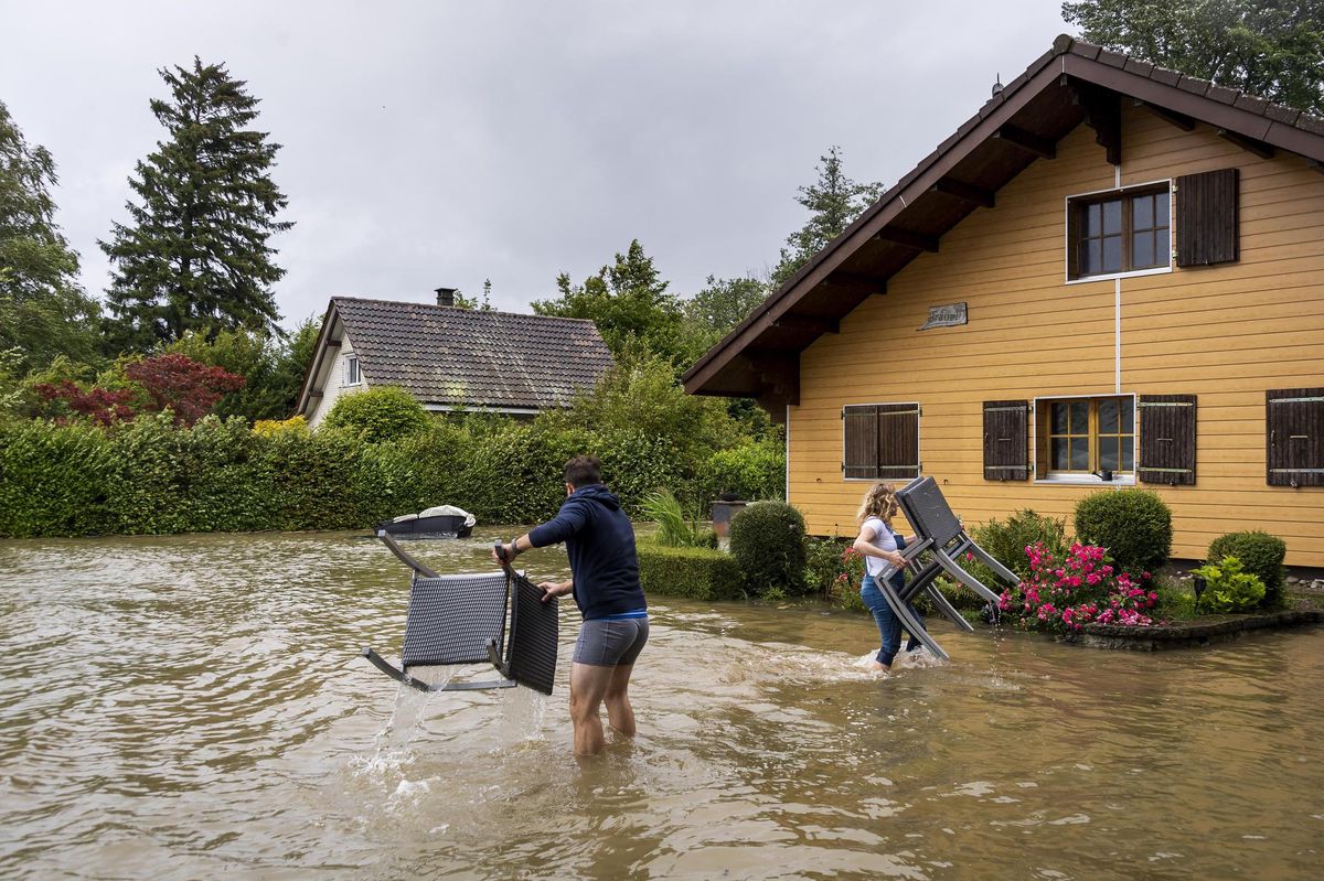 Deux résidents enlèvent du mobilier de jardin dans leur maison située sur les rives du lac de Bienne le jeudi 15 juillet 2021.