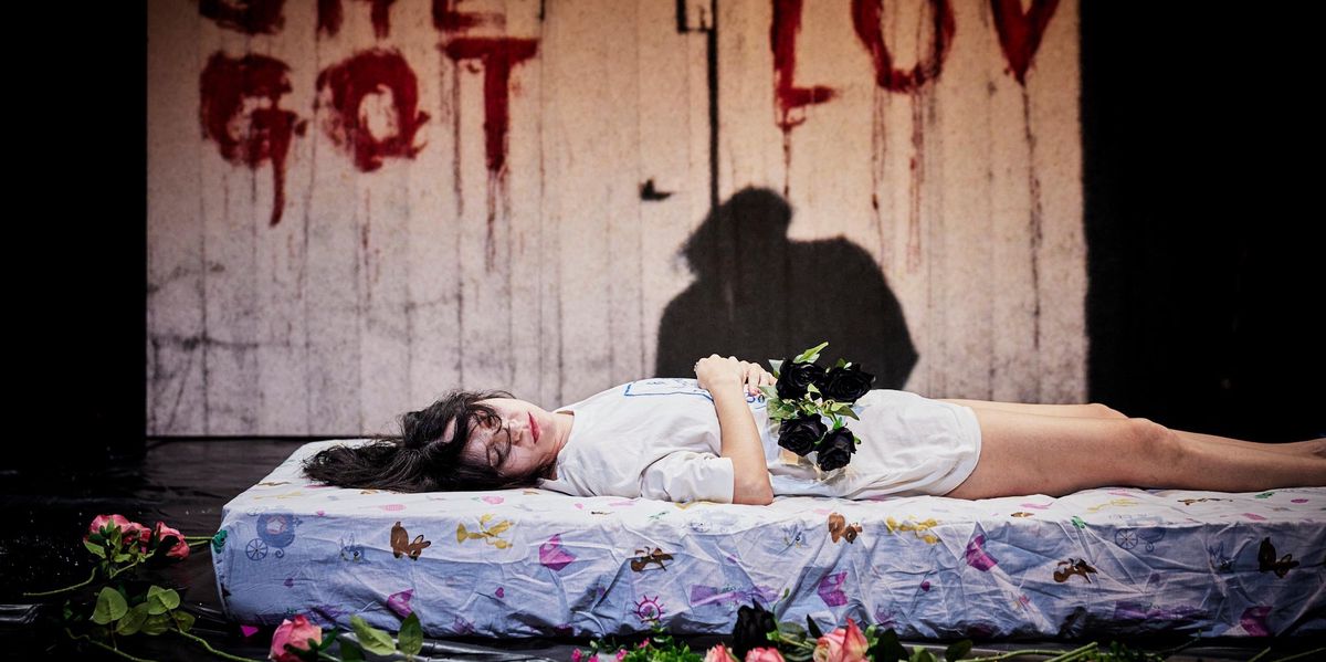 Une femme allongée sur un matelas, entourée de roses, avec l'inscription 'SHE GOT LOV' en arrière-plan.