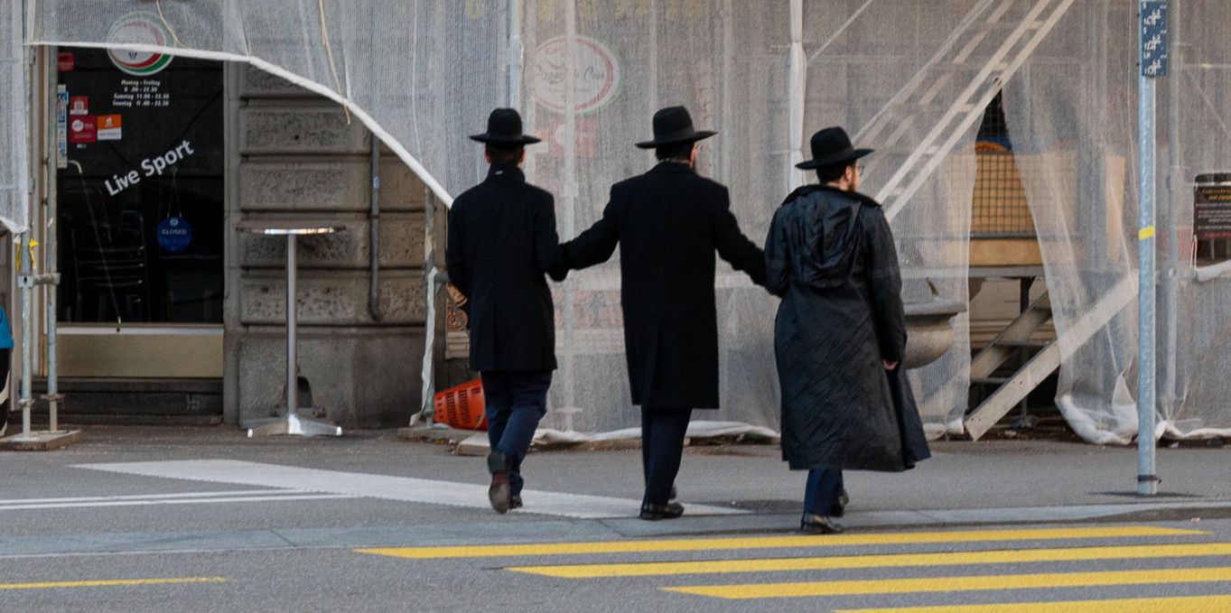 Trois hommes juifs arborant une tenue orthodoxe déambulent à Wiedikon.