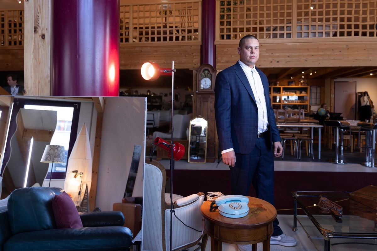 Jérôme Clémence, fondateur de Recyclage Market, debout dans un magasin de meubles d’occasion à Morges, entouré de divers articles comme des fauteuils et des luminaires, le 4 février 2025. (Odile Meylan/Tamedia)