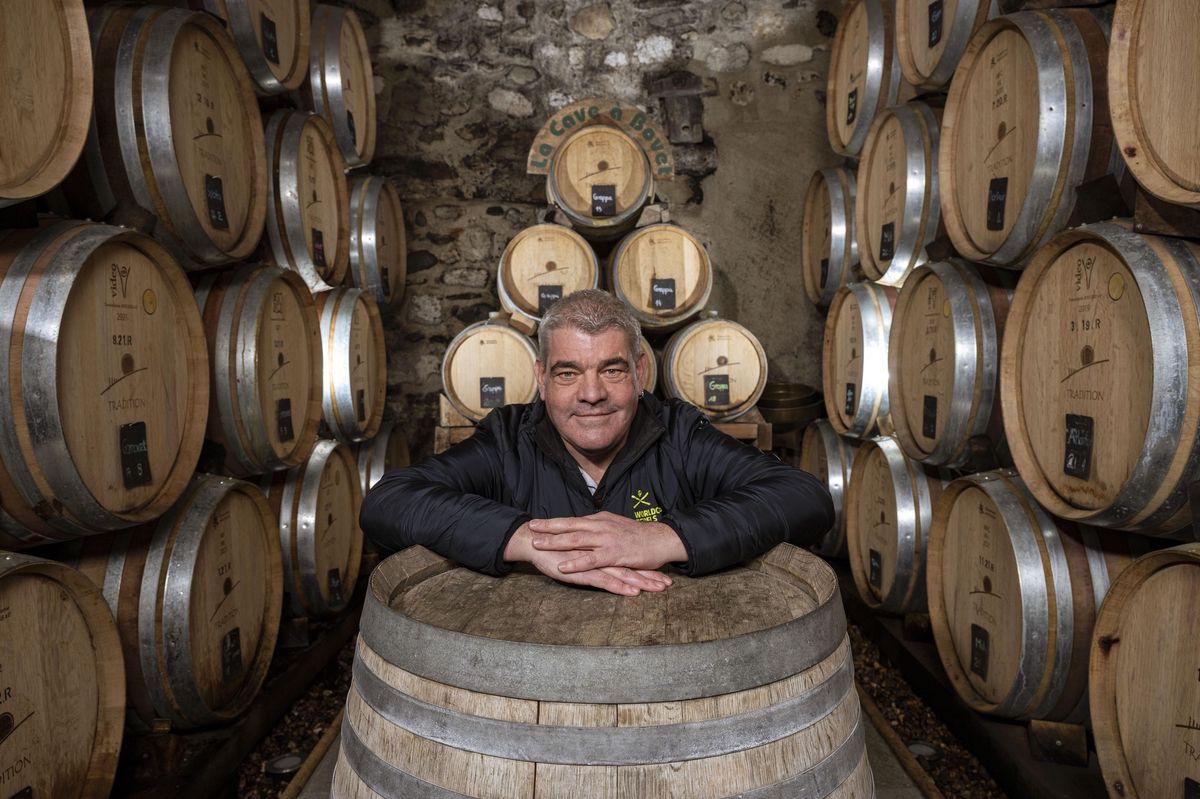 Philippe Bovet, vigneron multiprimé, pose dans une cave entourée de fûts de vin à Givrins.