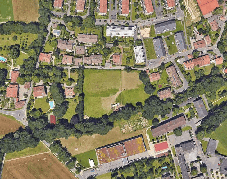 Vue aérienne de quartier résidentiel avec maisons, espaces verts, routes sinueuses et plusieurs piscines.