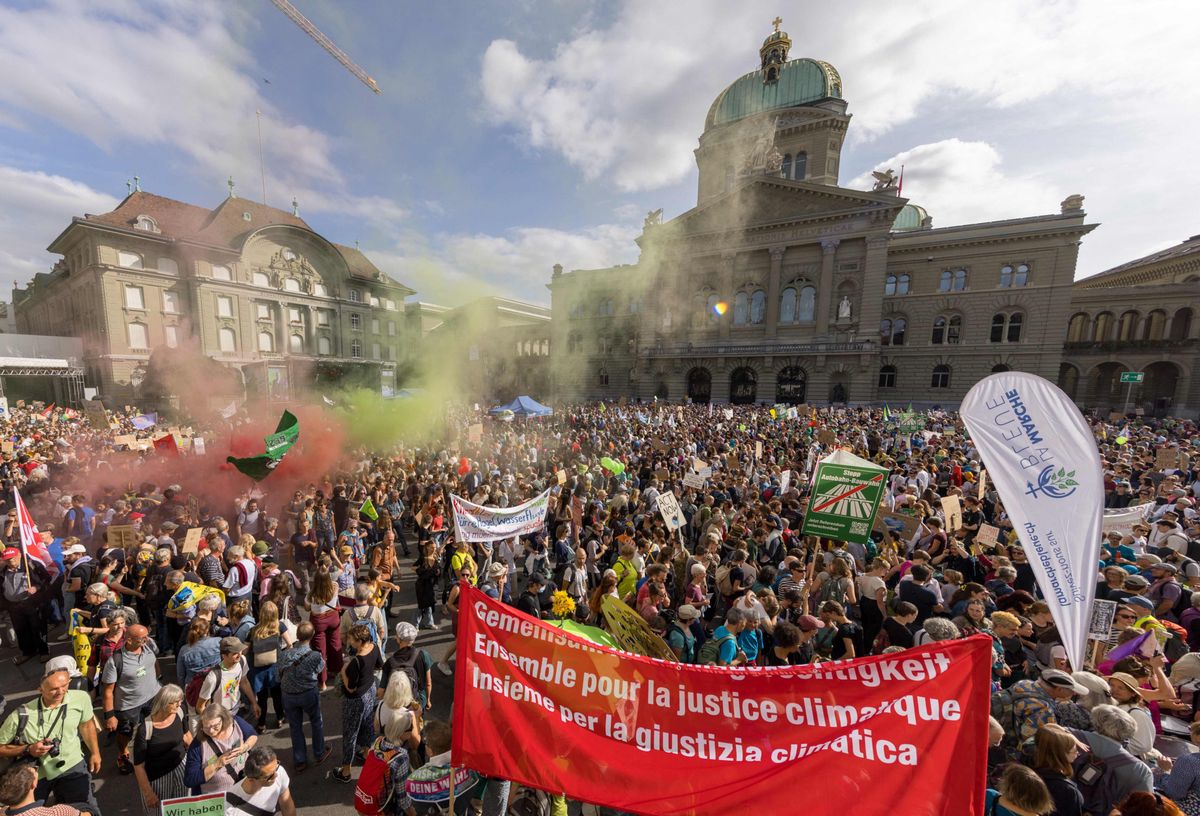 Demonstrators light flares next to the House of Swiss Parliament during a national protest for climate justice in Bern, on September 30, 2023. (Photo by Valentin Flauraud / AFP)