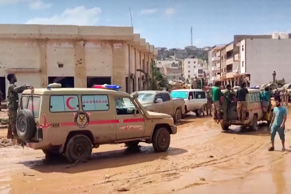 This image grab from footage published on social networks by Libyan al-Masar television channel on September 13 shows a Red Crescent ambulance moving with other vehicles along a muddy road in the wake of floods after the Mediterranean storm "Daniel" hit Libya's eastern city of Derna. A global effort to assist stricken Libya gathered pace on September 14 after a tsunami-like flood killed nearly 4,000 people and left thousands missing. Military transport aircraft from Middle Eastern and European nations, along with ships, have been ferrying emergency aid to the North African country already scarred by war. (Photo by Al-Masar TV / AFP) / === RESTRICTED TO EDITORIAL USE - MANDATORY CREDIT "AFP PHOTO / HO / AL-MASAR TV" - NO MARKETING NO ADVERTISING CAMPAIGNS - DISTRIBUTED AS A SERVICE TO CLIENTS ===