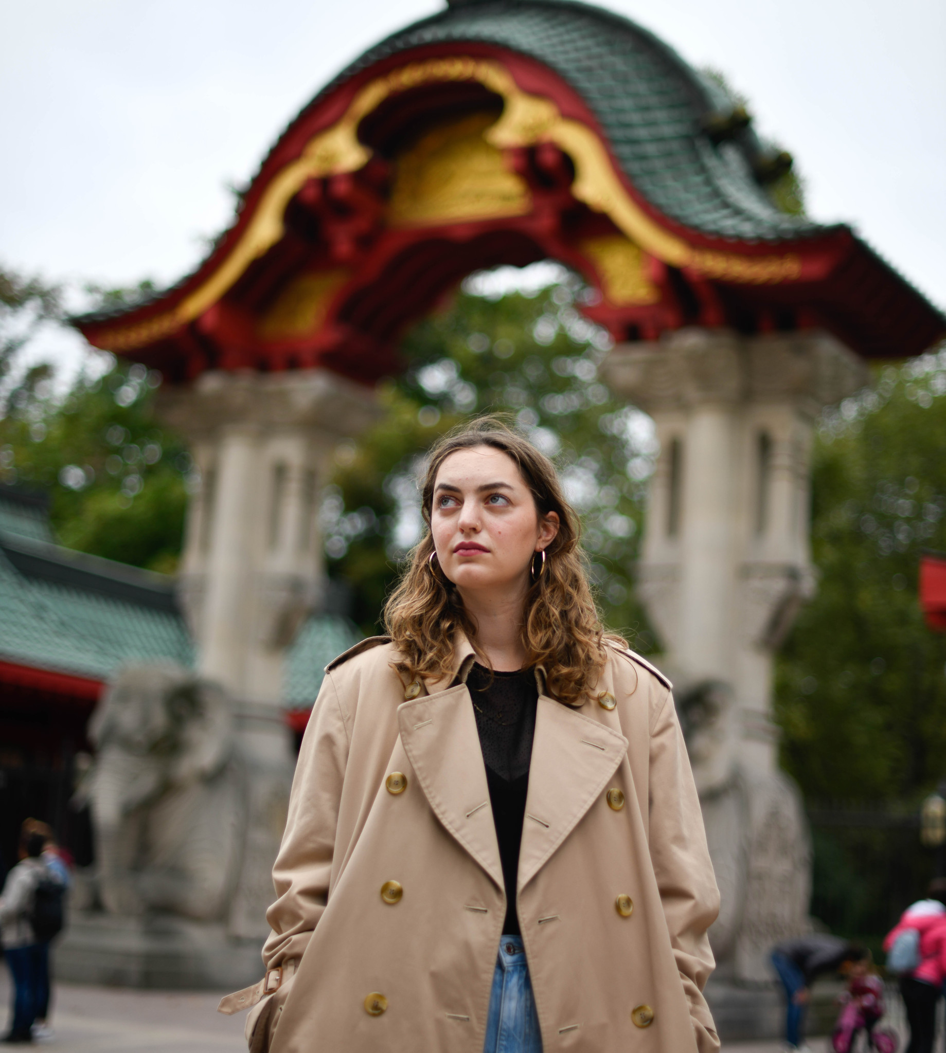 Schriftstellerin Dana Vowinckel in beigem Trenchcoat vor dem Elefantentor des Berliner Zoos.