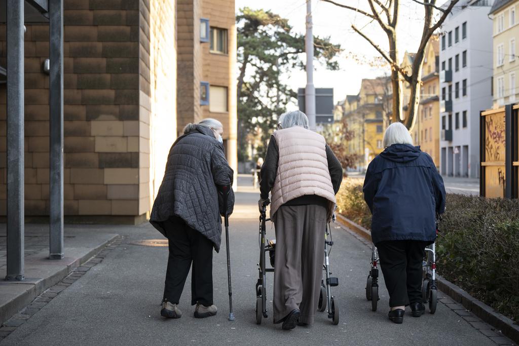 Trois femmes âgées marchent sur le trottoir.