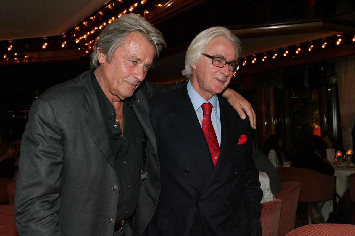 Deux hommes bien habillés marchent ensemble dans un cadre élégant avec des lumières en arrière-plan à Genève, le 6 mars 2005.