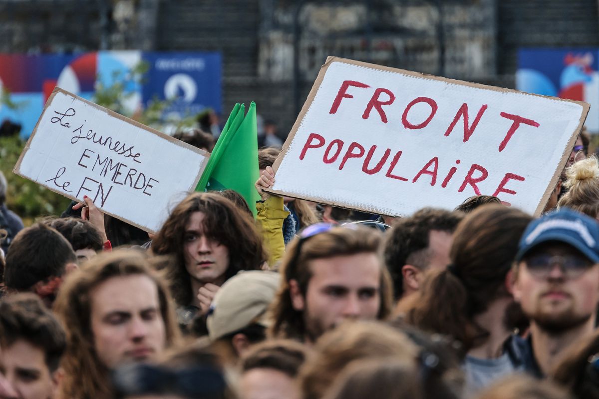 Protesters hold placards which read "The Youth say 'screw you' to the National Front" and "Popular Front" as they gather on the Place de la Republique to demonstrate against the victory of the French far-right party Rassemblement National (RN)National (RN) in the European elections, taking a position of strength in the early legislative elections called by French President after the election results, in Lille (northern France), on June 10, 2024. Analysts say the French leader has taken the extremely risky gamble of dissolving the national parliament in a bid to keep the far-right Rassemblement National (RN) party out of power when his second term ends in 2027, after the far right crushed his centrist alliance in the June 9, 2024 EU ballot. The announcement sparked widespread alarm across France, even from within the ranks of his own party. (Photo by Denis CHARLET / AFP)