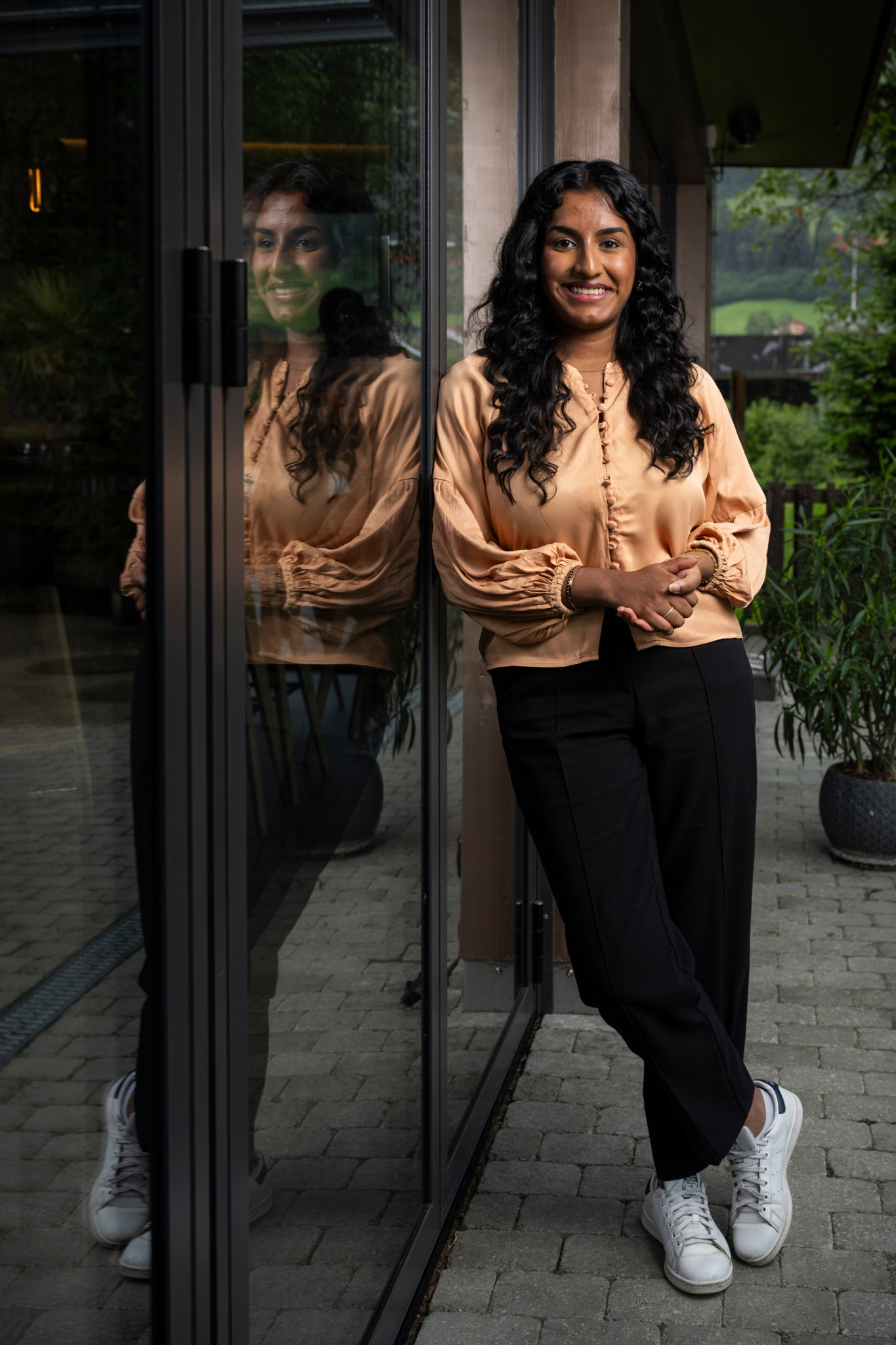 Hanishha Soosai, 23, UN-Jugenddelegierte der Schweiz, steht in Frutigen vor einem Glasfenster.