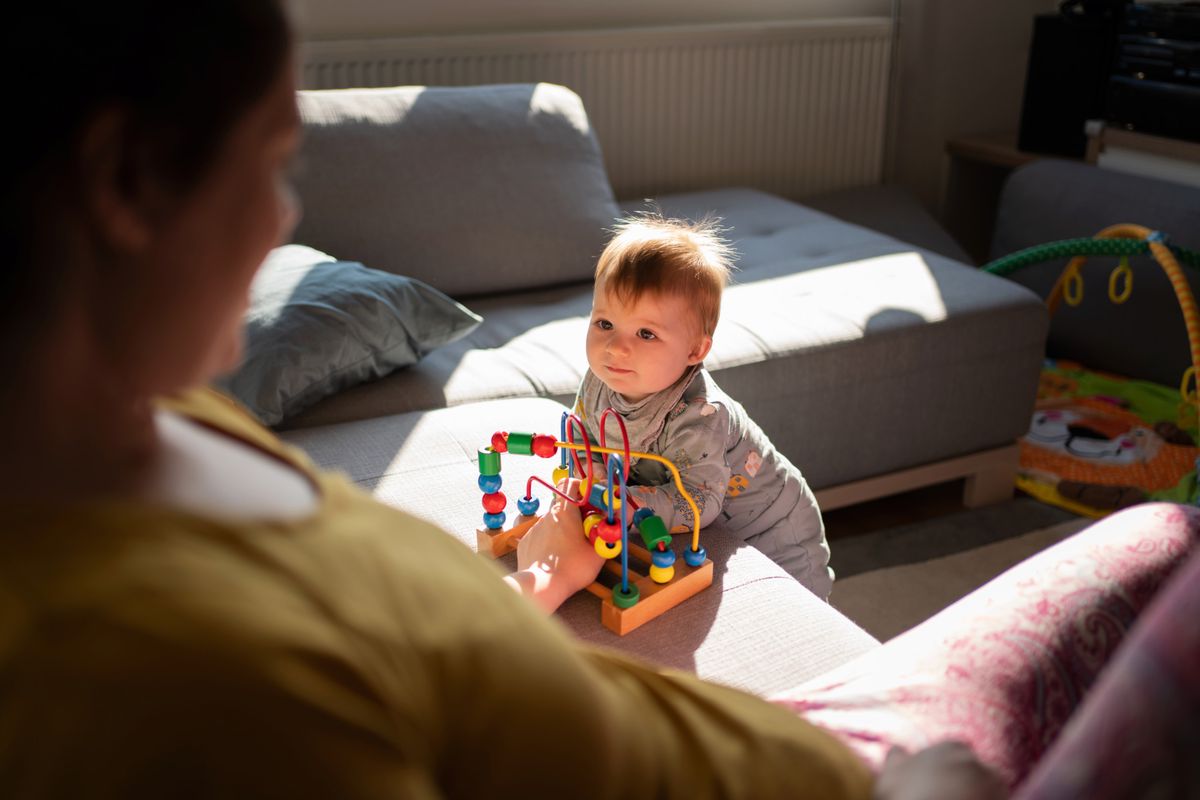 Vue en plongée d'une mère non identifiable et de son bébé jouant avec un jouet et se regardant.