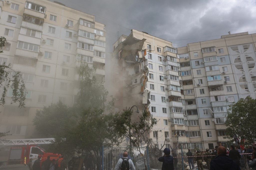 Une vue d'un immeuble d'appartements partiellement effondré à Belgorod, endommagé par une frappe ukrainienne le 12 mai 2024. De la fumée et des débris sont visibles, avec des services d'urgence présents sur les lieux.