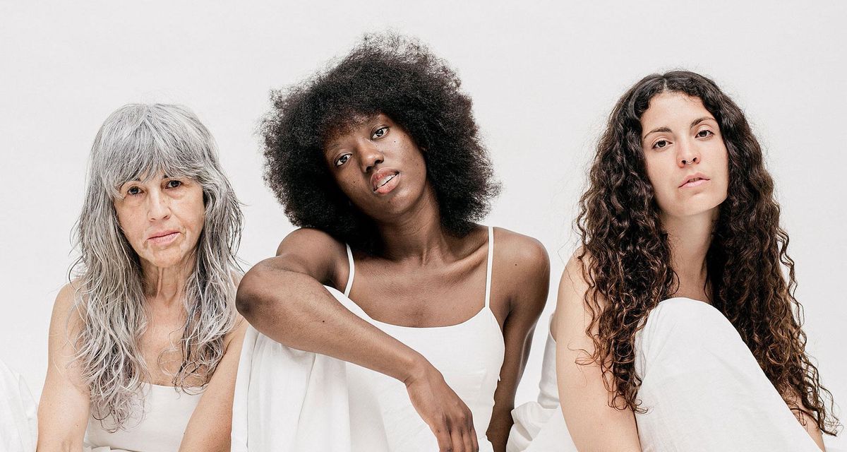 Trois femmes d'âge différent posent sur un fond blanc